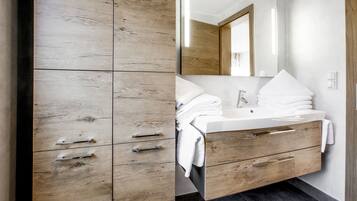 A modern bathroom with a wooden vanity, a sink, and a mirror.