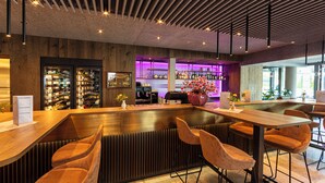 A modern bar area with wooden furniture, a counter, and a seating area with bar stools. - Aktiv Hotel Schweizerhof - Kitzbühel (Kitzbuhel)