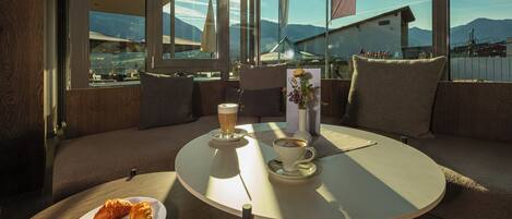 A cozy seating area with a table, a plate of croissants, a cup of coffee, and a glass of beer.