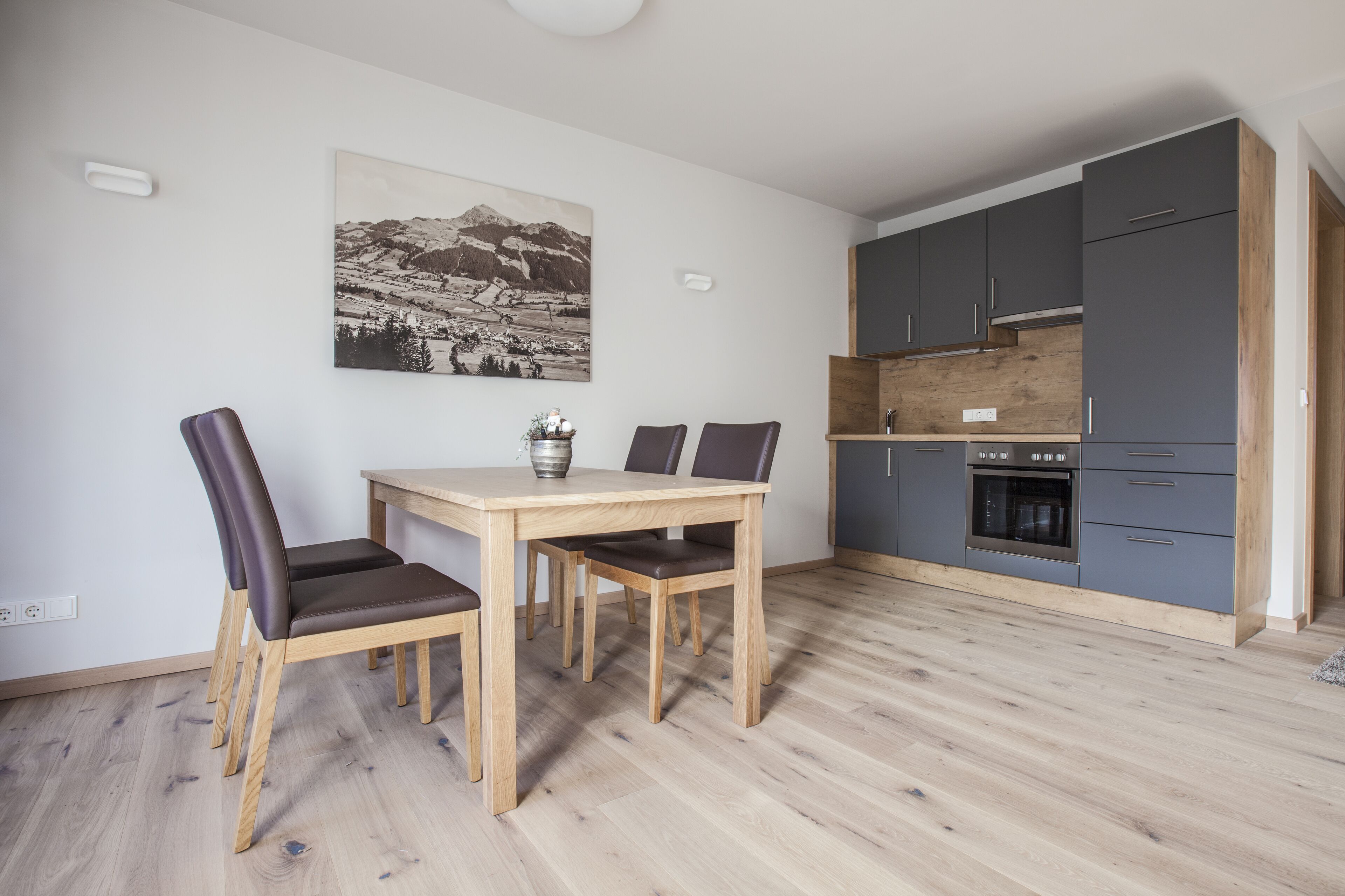 A modern kitchen with grey cabinets, a wooden countertop, and a built-in oven.