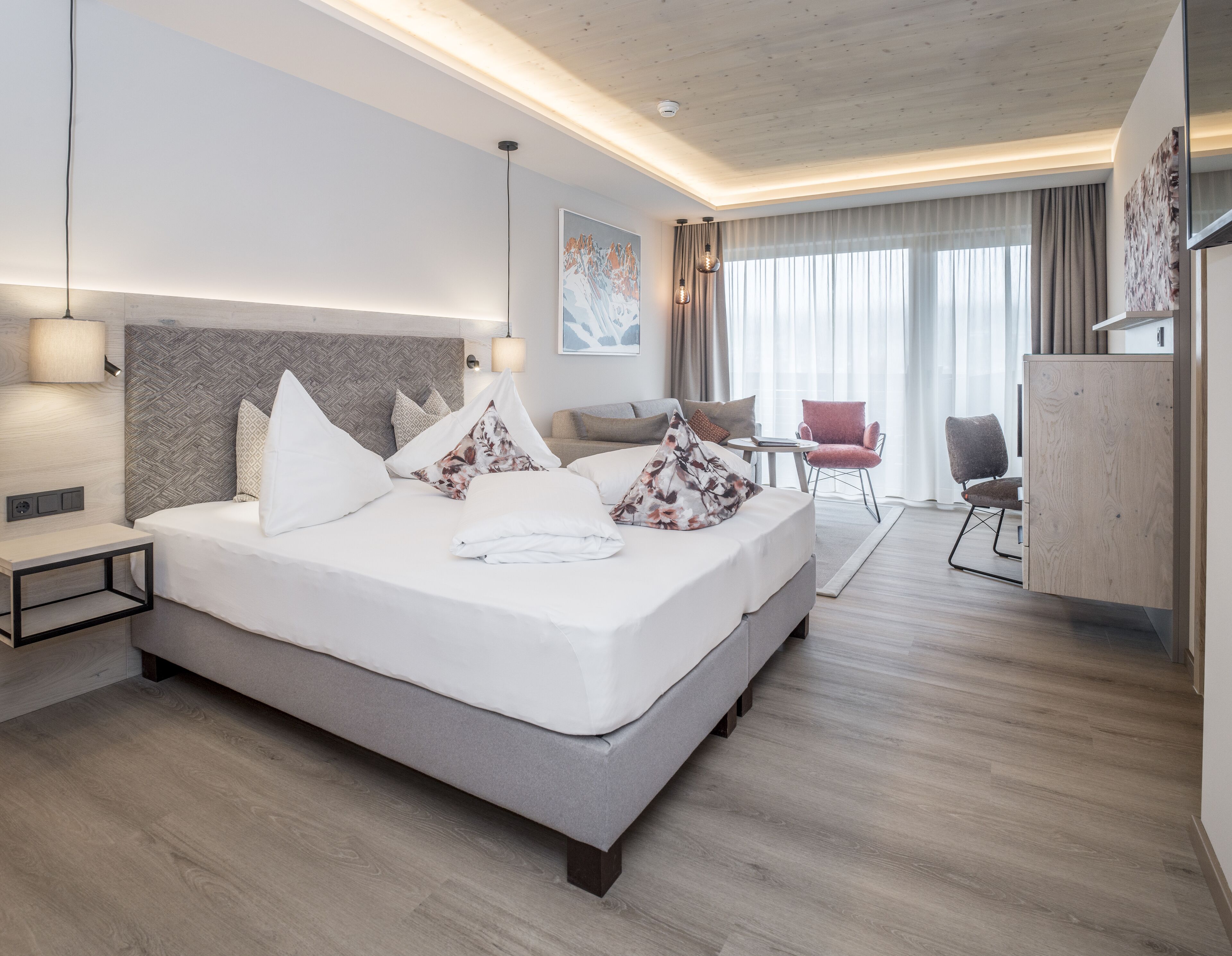 Una habitación de hotel moderna con una cama grande, mesitas de noche, un escritorio y una silla.