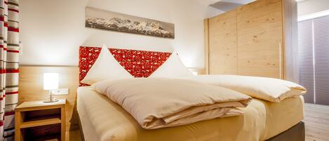 Habitación de hotel con cama, mesita de noche, armario de madera y ventana con persianas.