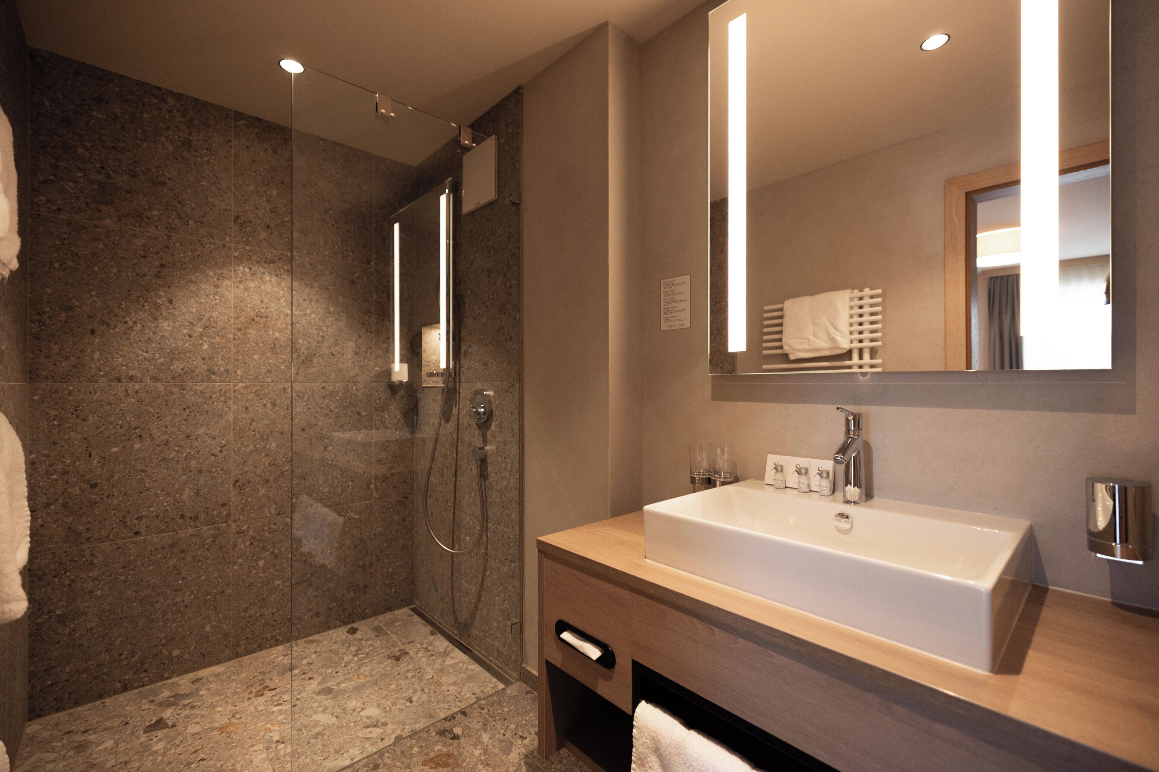 Un baño moderno con un lavamanos grande, una cabina de ducha con mampara de vidrio y un espejo.