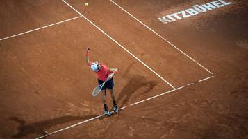 A tennis player on a clay court with "MITZBUHEL" written on the surface.