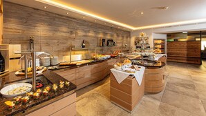 A modern breakfast buffet with a wooden wall backdrop, a variety of food items, and a clean, contemporary design. - Aktiv Hotel Schweizerhof - Kitzbühel (Kitzbuhel)