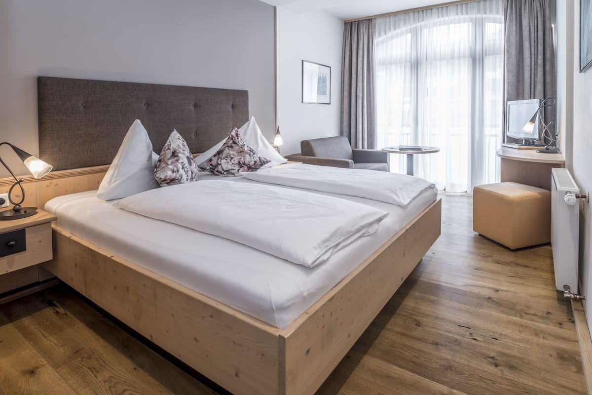 Quarto de hotel moderno com uma cama grande, mesas de cabeceira, uma escrivaninha e uma cadeira.