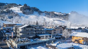 A hotel with a modern design, located in a snowy mountainous area with ski slopes in the background. - Aktiv Hotel Schweizerhof - Kitzbühel (Kitzbuhel)