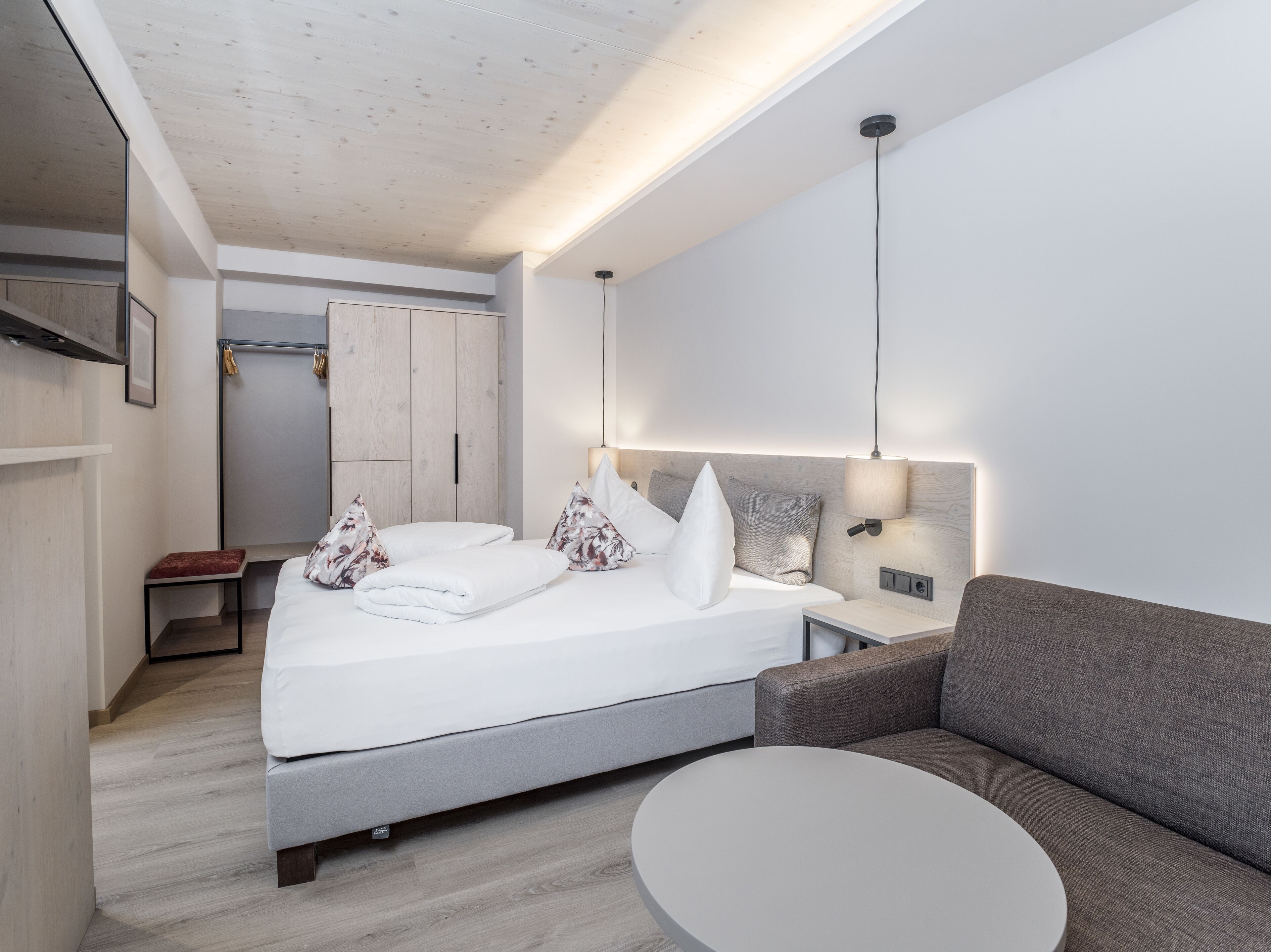Une chambre d’hôtel moderne équipée d’un lit, d’un canapé, d’une petite table et d’une armoire.