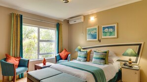 A bedroom with a bed, a chair, a table, and a nightstand.