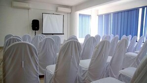 A conference room with rows of chairs covered in white cloths, a whiteboard, and a speaker. - Costa Brava (Manzanillo)