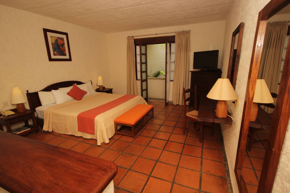 Ein Hotelzimmer mit einem Bett, Nachttischen, einem Schreibtisch und einem Fernseher.
