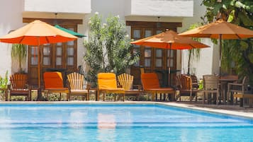 Una piscina al aire libre, sombrillas, sillones reclinables de piscina