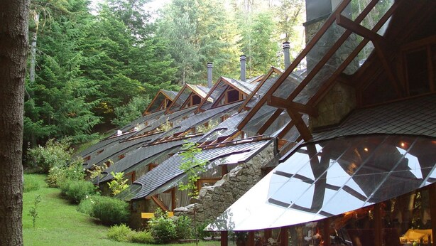 A row of log cabin-style buildings with sloped roofs and large windows, surrounded by lush greenery. - Casa del Bosque Apart, Suites & Spa (Villa La Angostura)