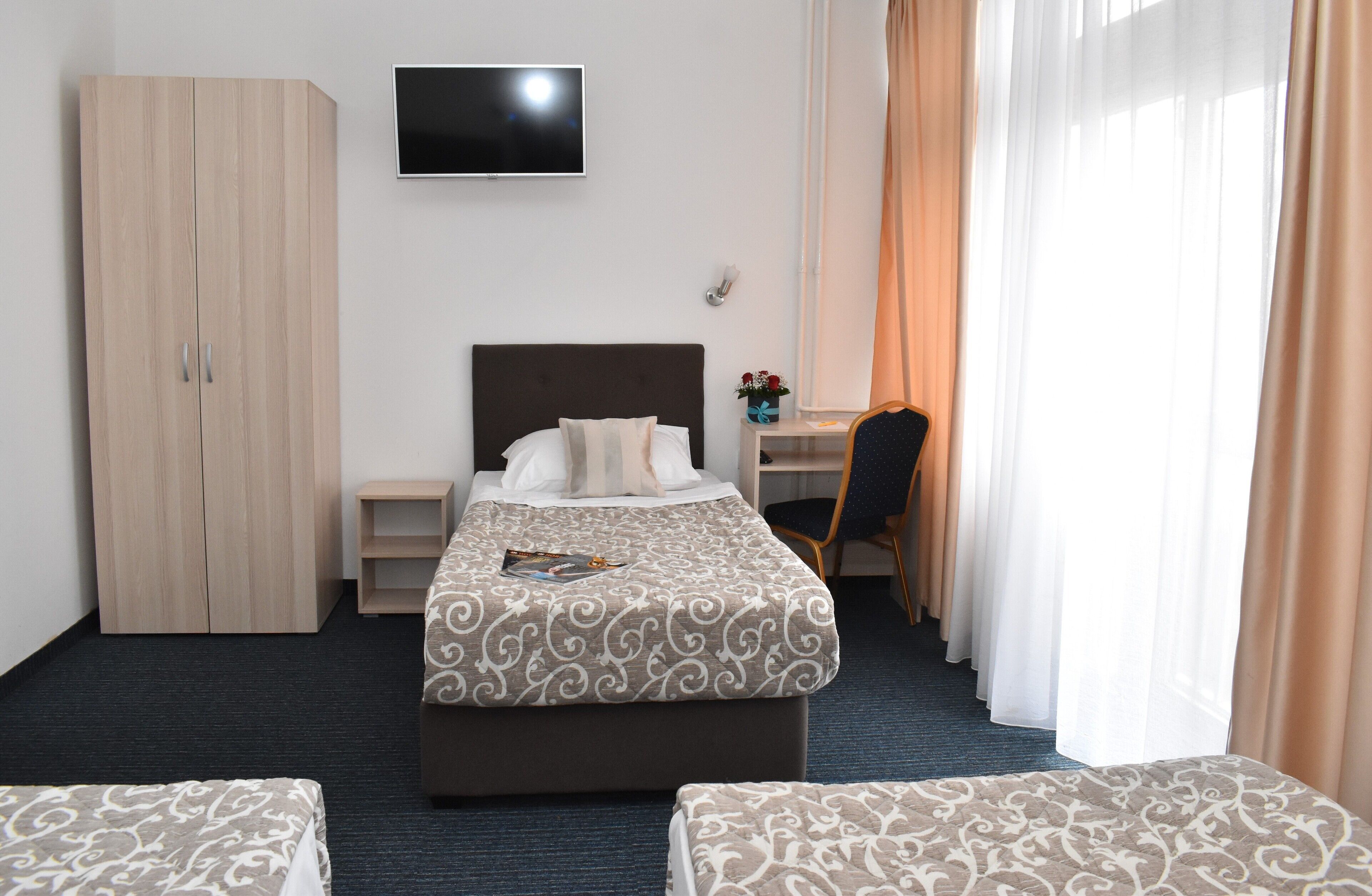 Une chambre d’hôtel équipée d’un lit, d’un bureau, d’une chaise, d’une armoire et d’un téléviseur.