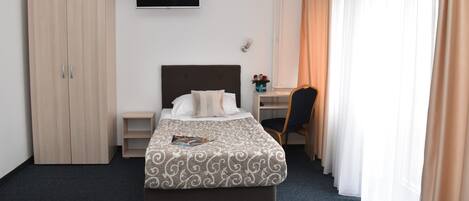 Une chambre d’hôtel équipée d’un lit, d’un bureau, d’une chaise, d’une armoire et d’un téléviseur.