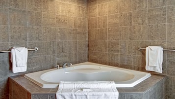 A modern bathroom with a freestanding bathtub, tiled walls, and towel racks.