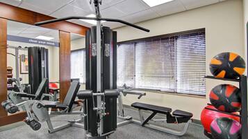 Een sportschool met diverse fitnessapparaten, waaronder een squatrek en banken.