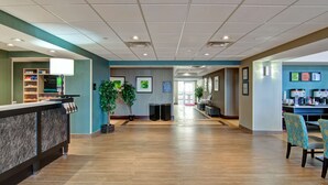 A spacious lobby with a reception desk, a seating area, and a counter with various items. - Hampton Inn by Hilton Sudbury (Sudbury)
