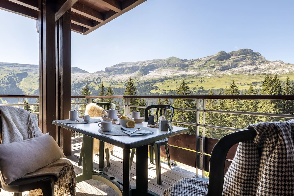 Ein Balkon mit Tisch für zwei Personen, mit Blick auf eine Berglandschaft.