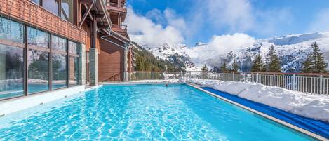 A swimming pool with a view of snow-covered mountains and a clear sky.
