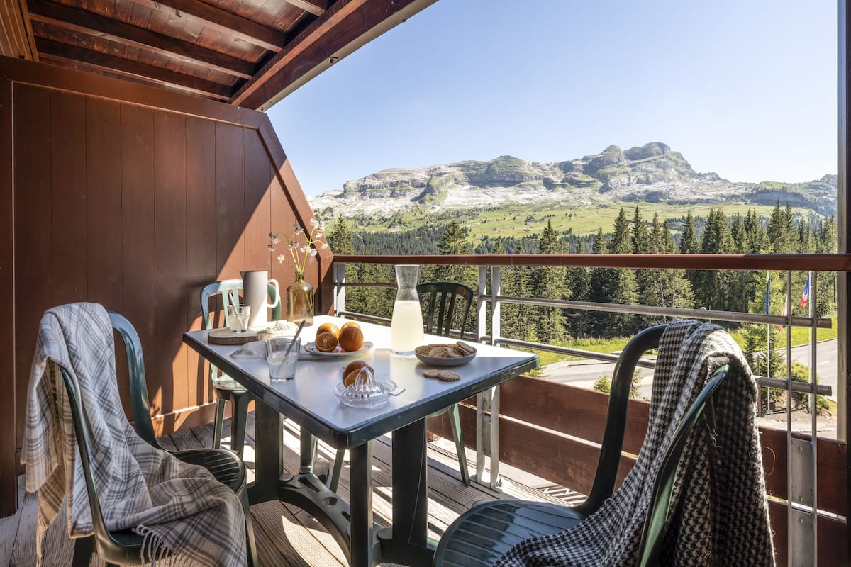 Ein Balkon mit Frühstückstisch, mit Blick auf eine gebirgige Landschaft.