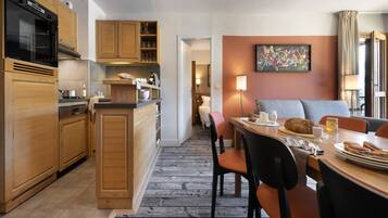 A modern kitchen with wooden cabinets, a built-in oven, and a dining area with a table set for breakfast.