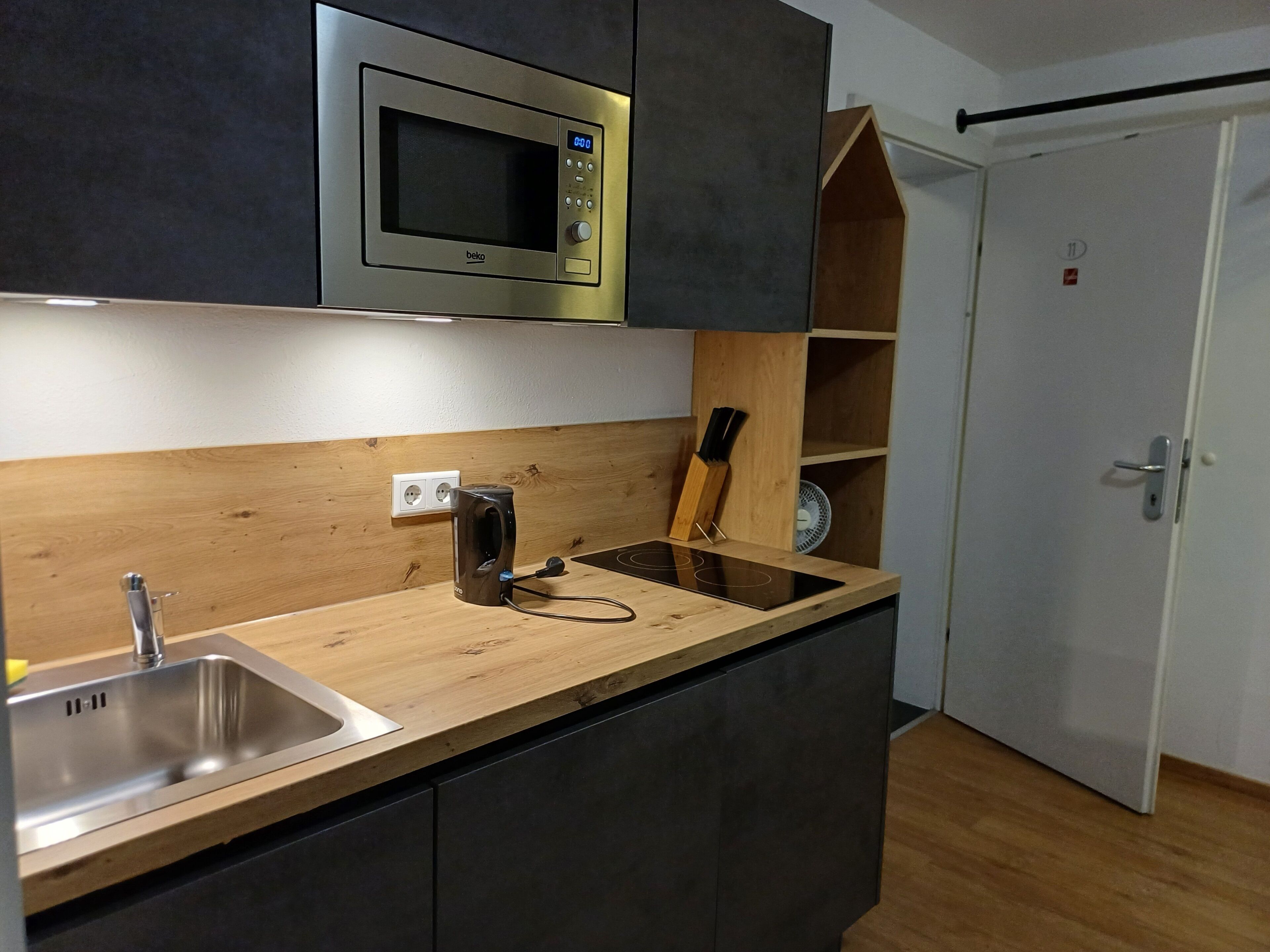 Eine moderne Küche mit integriertem Mikrowellenherd, einer Spüle und einer Holz Arbeitsplatte.