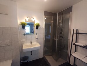 Een bad/douchecombinatie, een haardroger, handdoeken