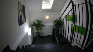 Un escalier surmonté d’une lucarne, une plante en pot et un mur végétal.