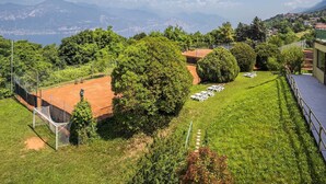Cancha de tenis rodeada de exuberante vegetación y vista a montañas distantes.