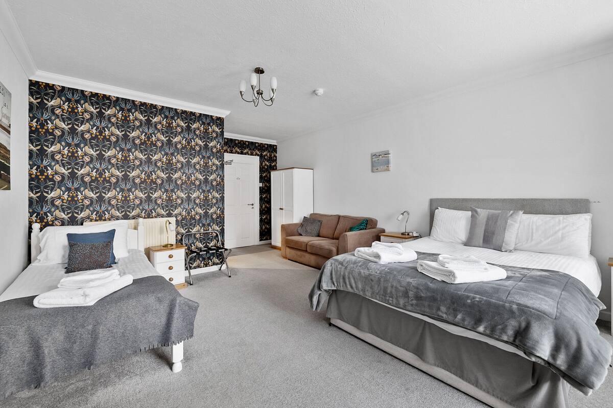 A bedroom with a bed, a chair, a bedside table, and a wardrobe.