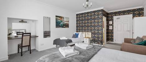 A bedroom with a bed, a desk, a chair, a nightstand, and a door.