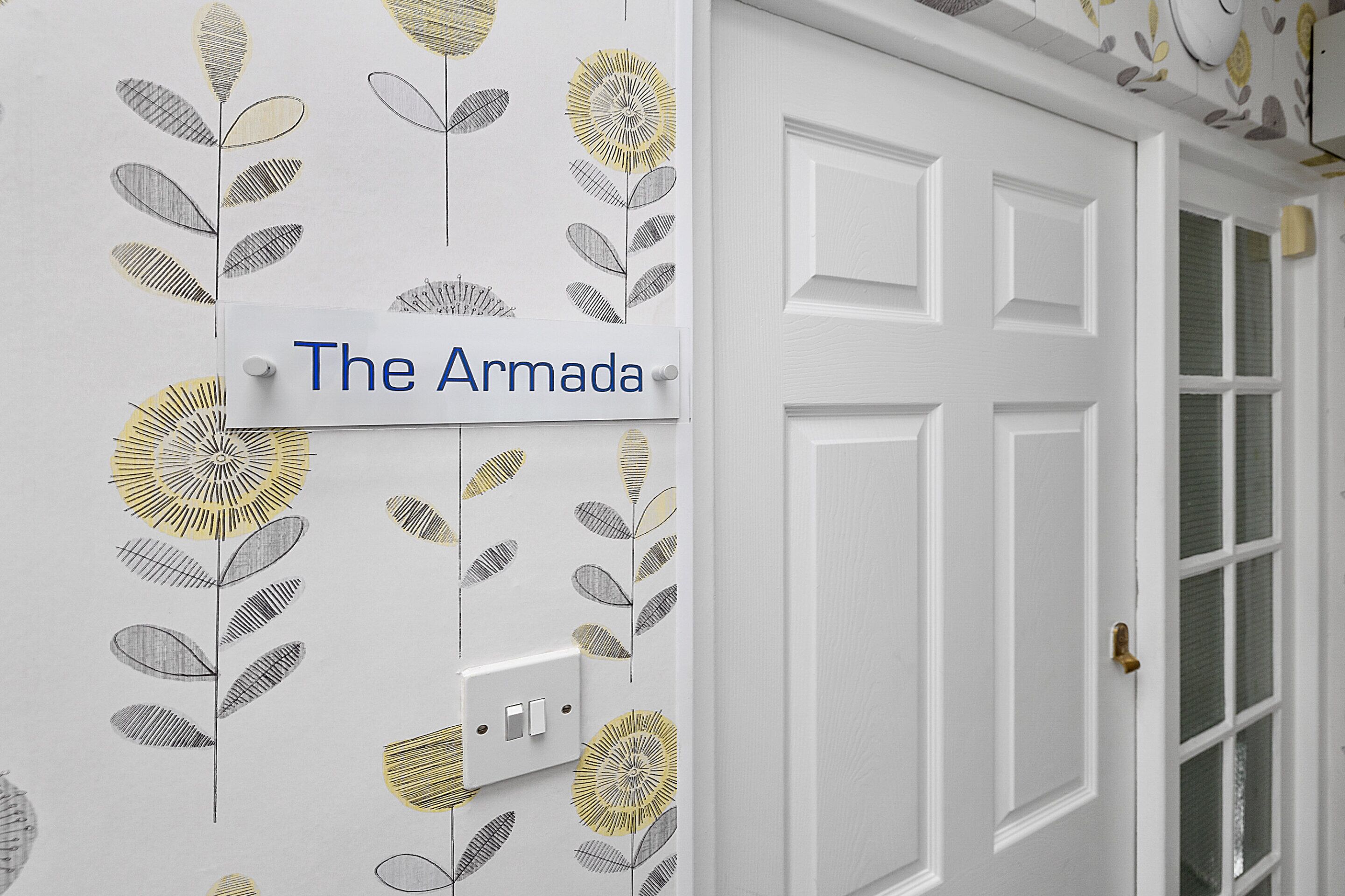 A door with a sign reading "The Armada" and a decorative floral pattern on the wall.