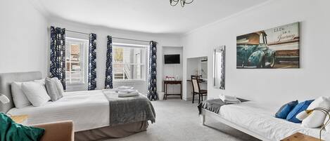 A modern bedroom with two beds, a desk, and a chair.