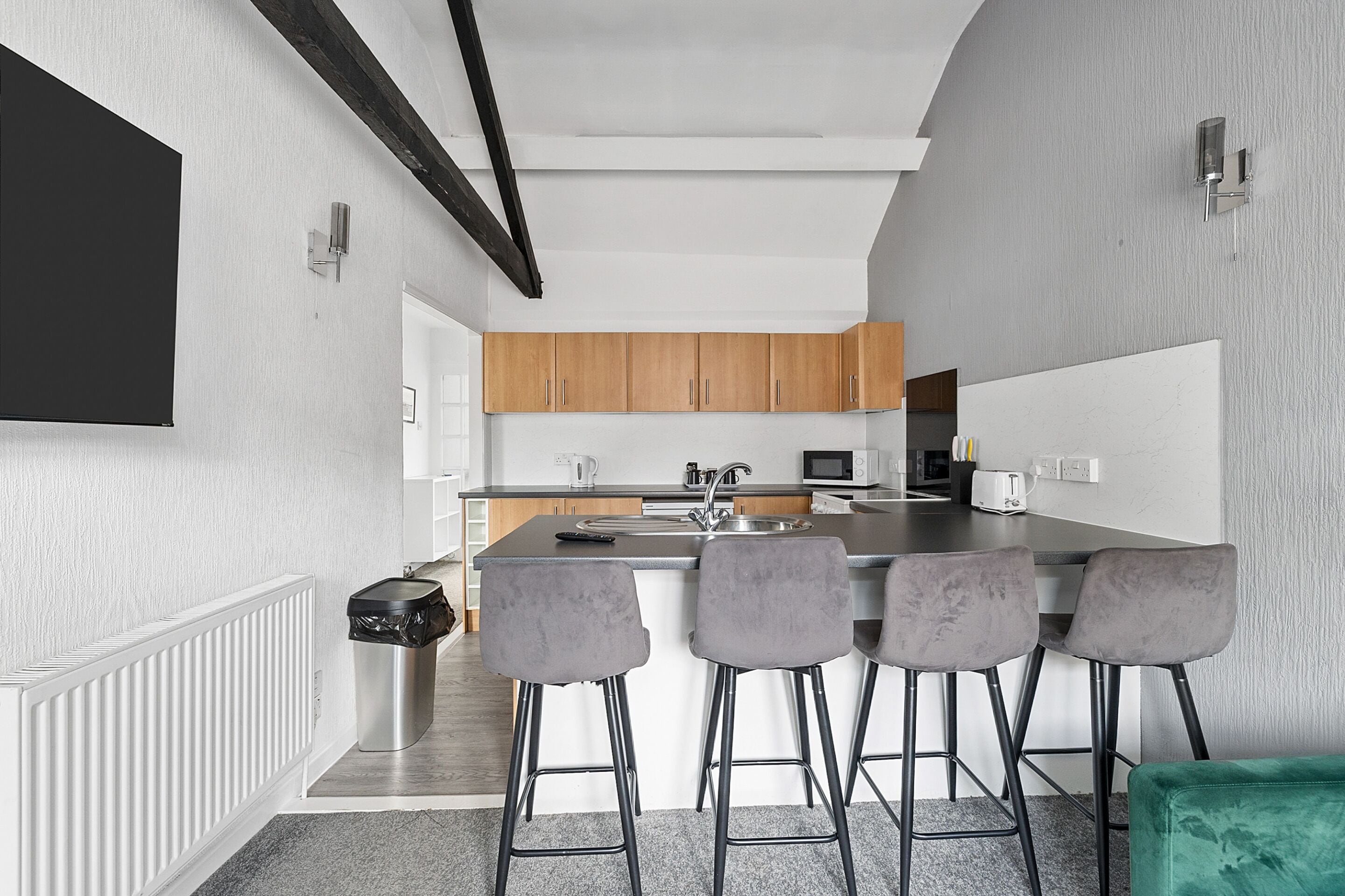A modern kitchen with grey bar stools, wooden cabinets, and a large island.