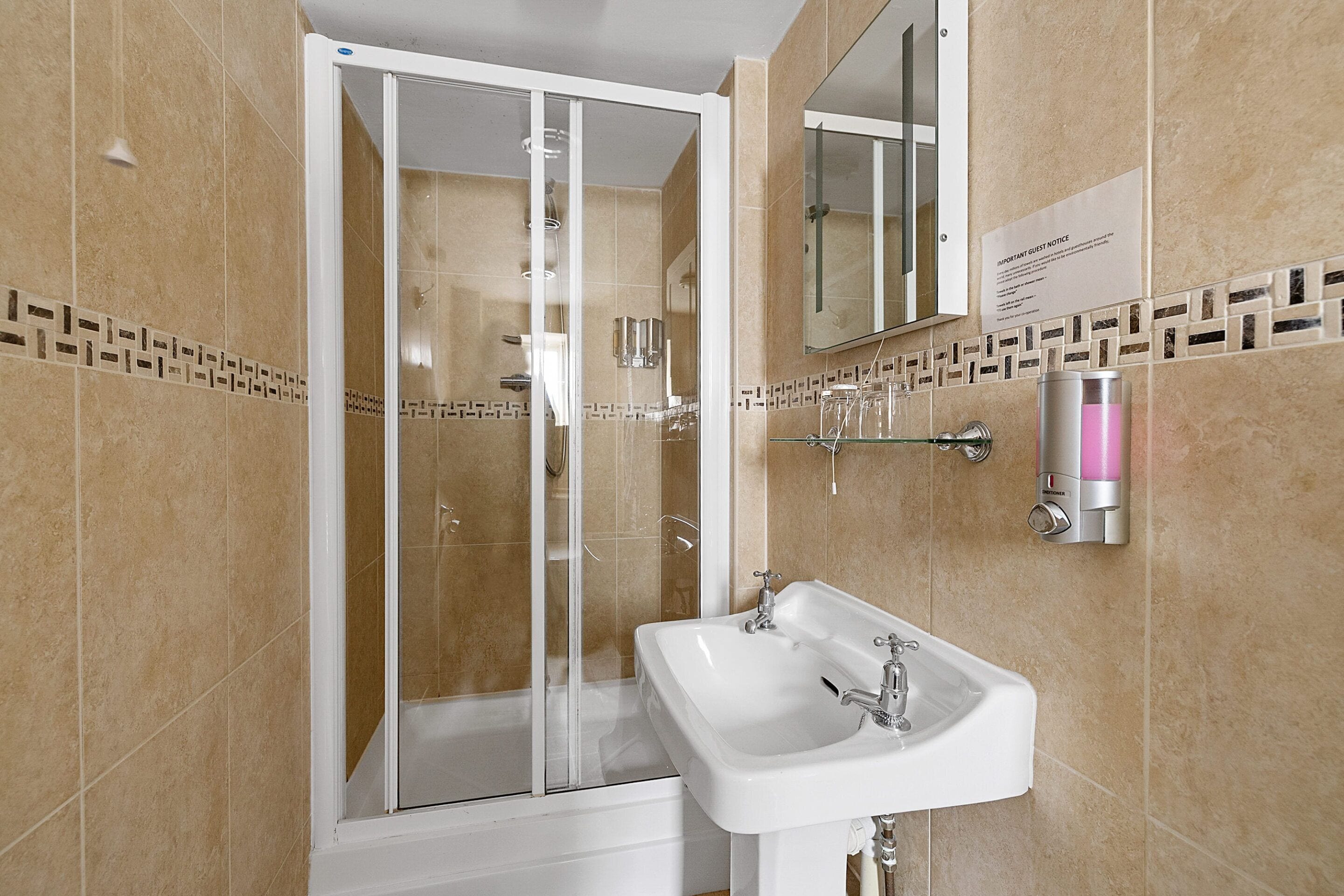 A modern bathroom with a glass-enclosed shower, a white sink, and a mirror.