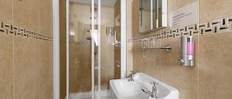 A modern bathroom with a glass-enclosed shower, a white sink, and a mirror.