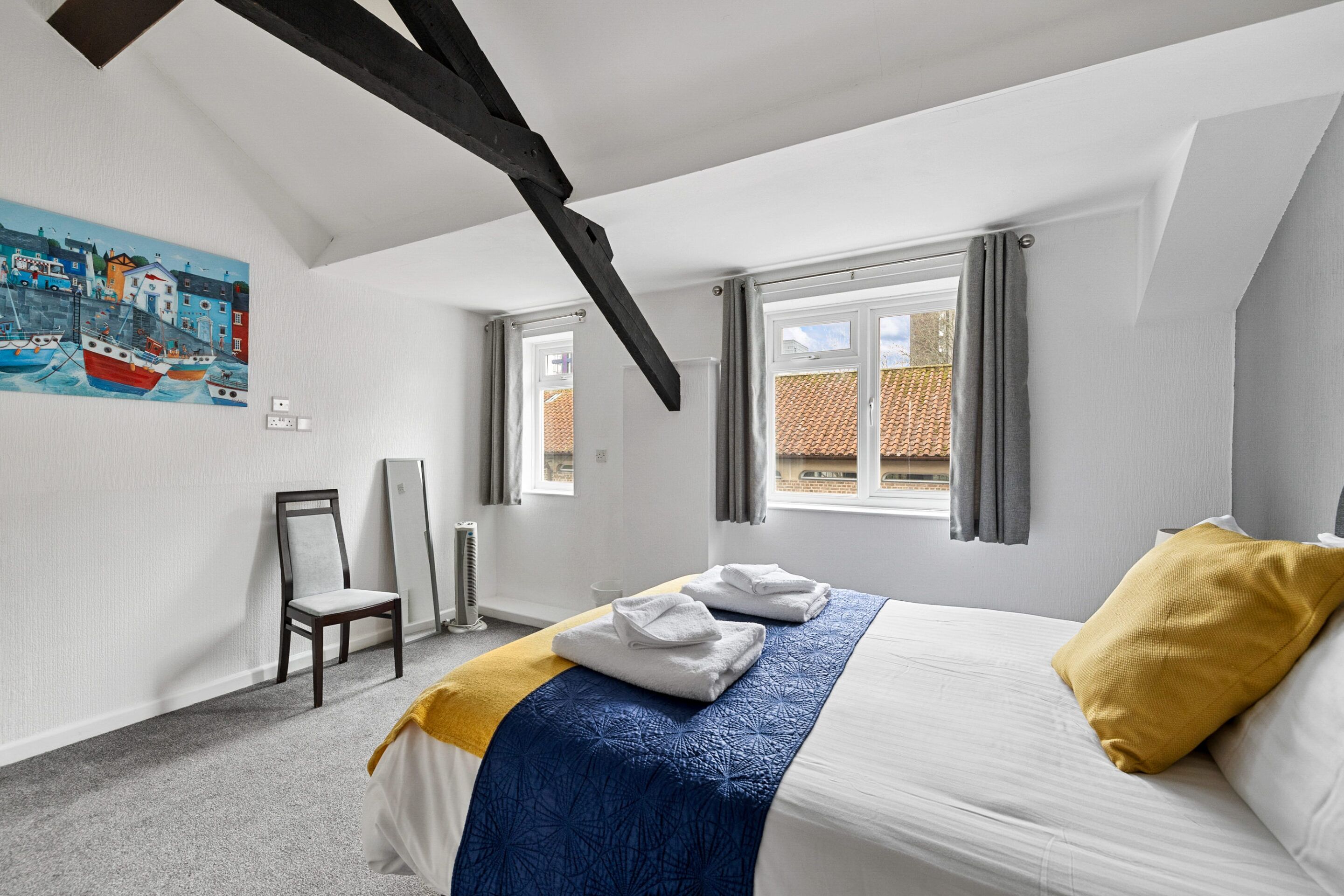 Ein Schlafzimmer mit einem Bett, einem Sessel, einem Gemälde und einem Fenster.