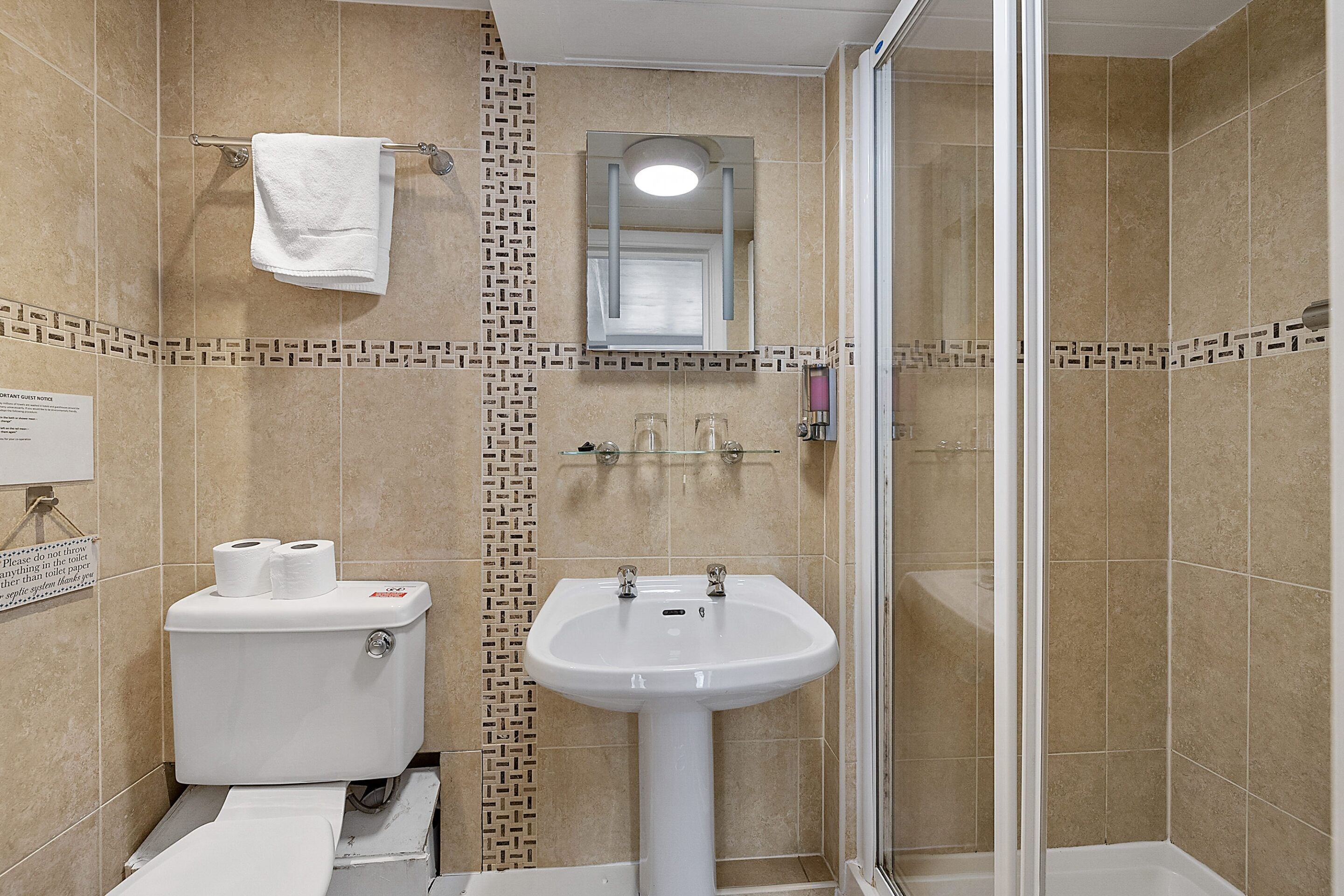 A bathroom with a toilet, sink, and shower.