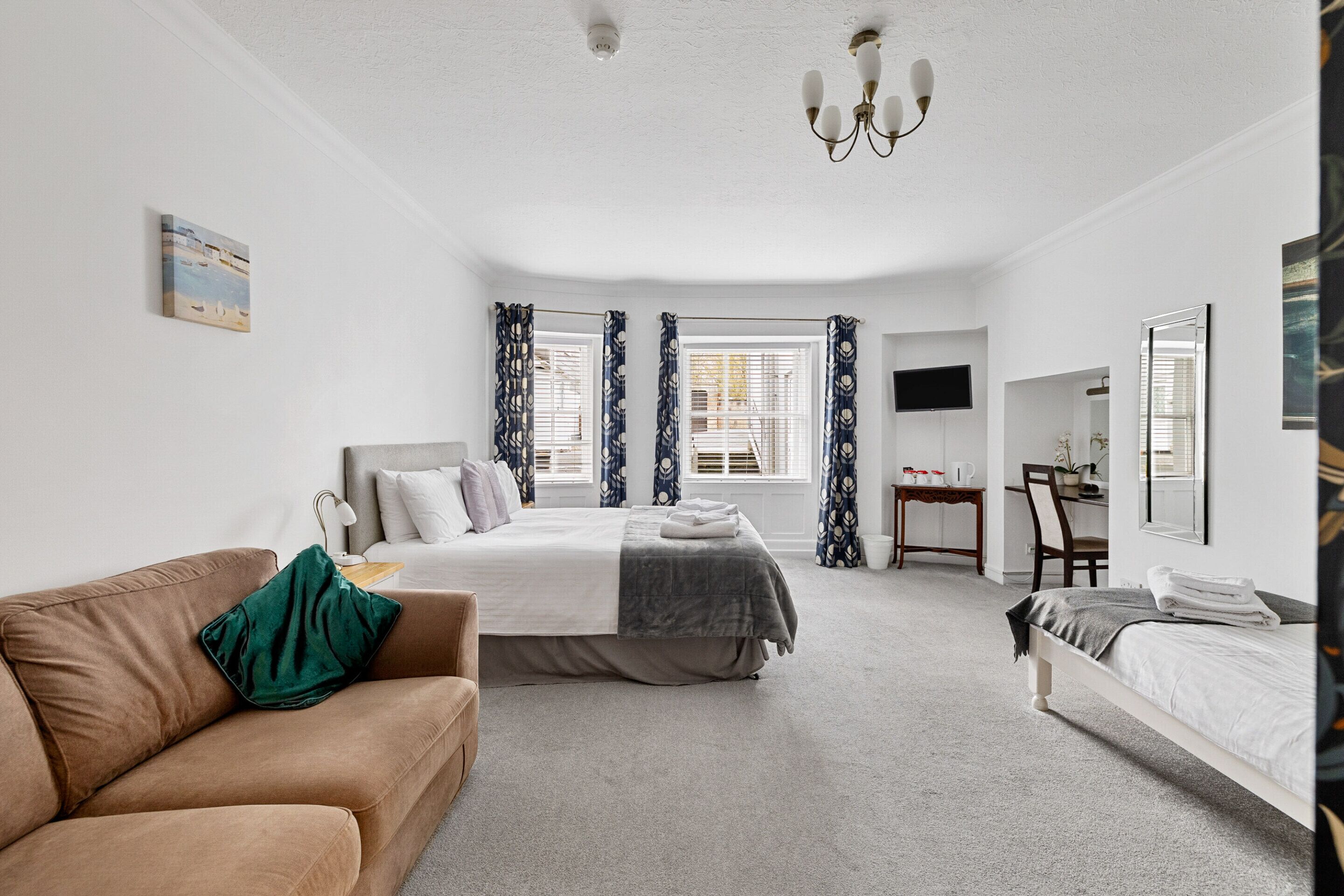 A bedroom with a bed, a sofa, a desk, and a chair.