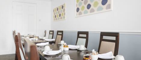 A dining table set for a meal with chairs, plates, cutlery, and a salt and pepper set.
