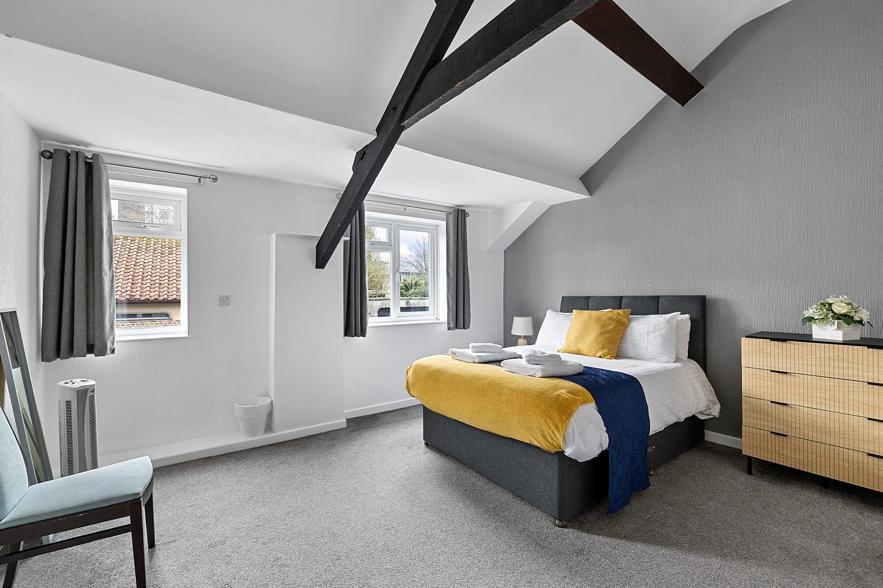 Un dormitorio con cama, cómoda y silla.