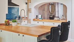 Una cocina moderna con encimera de madera, armarios blancos y una silla negra.