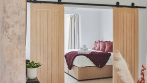 Un dormitorio con un armario de madera, una cama con una colcha roja y una planta en maceta.