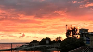 Ein Sonnenuntergang über einem Ufer mit einer Backsteinmauer und einem Holzsteg.