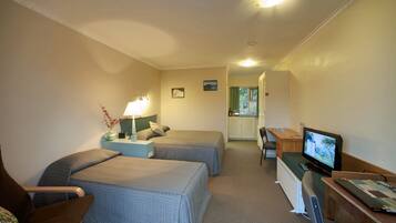 A hotel room with two beds, a desk with a computer, a chair, and a television.