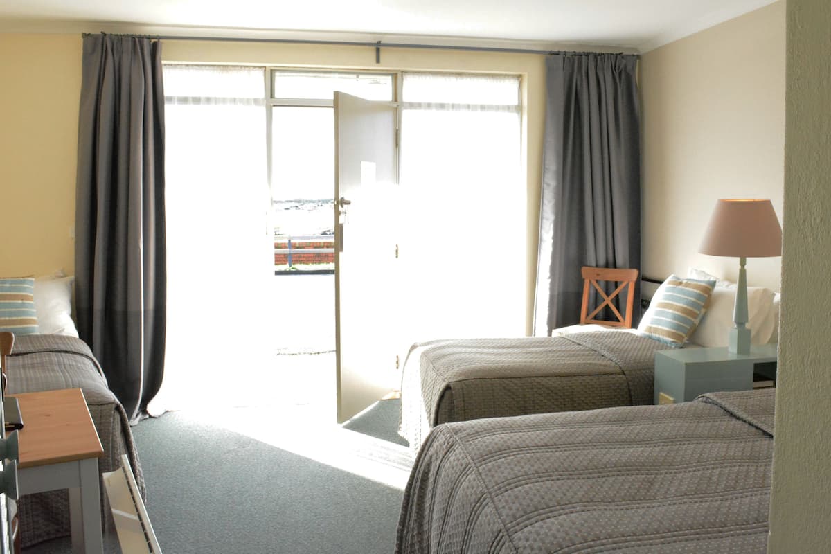 Habitación de hotel con dos camas, un escritorio, una silla y vistas al exterior.