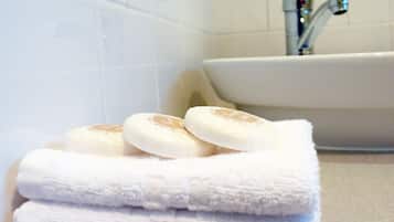 Una pila de toallas blancas y dos jabones sobre una encimera de baño.