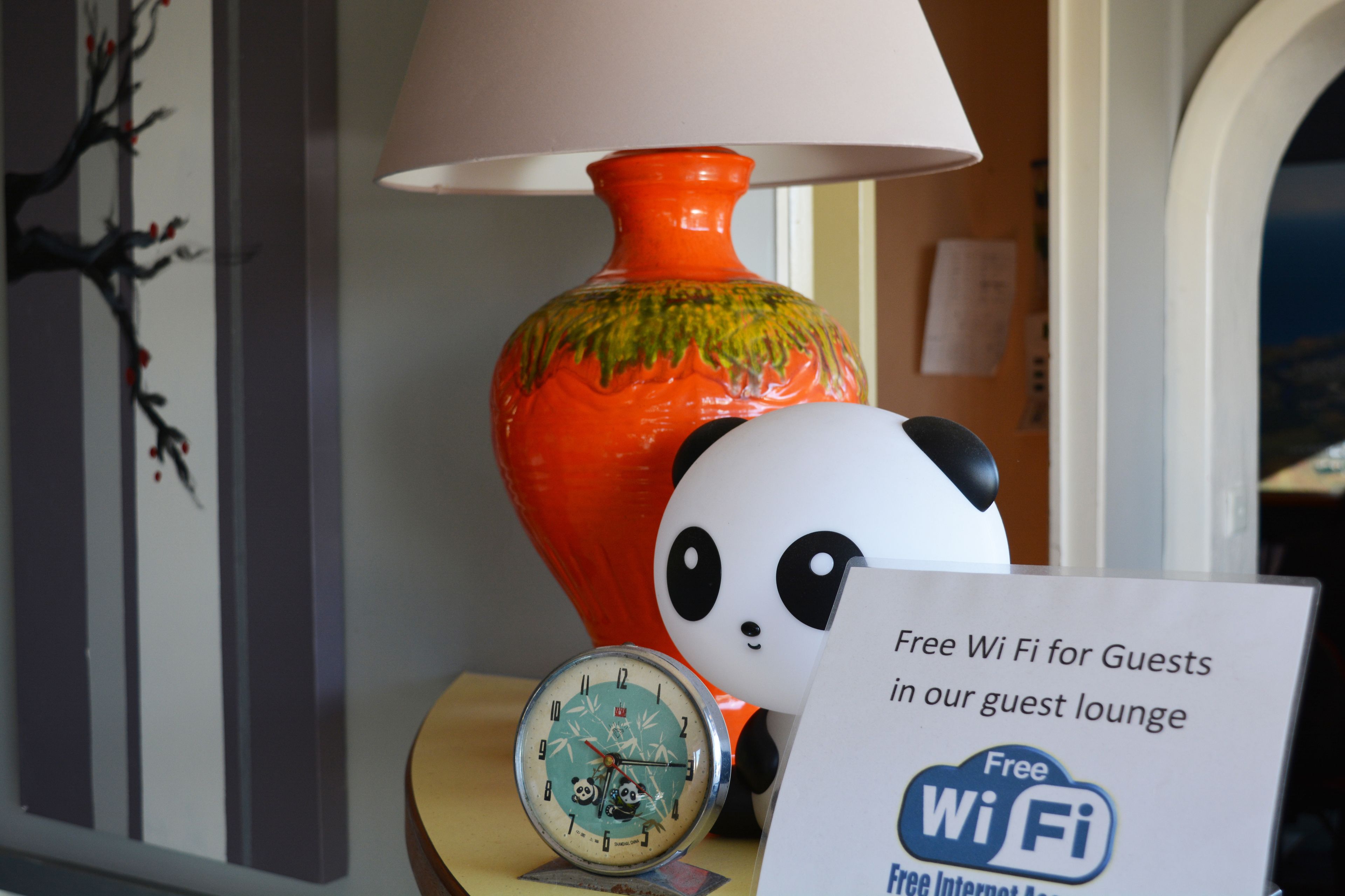 A panda figurine, a clock, and a sign offering free Wi-Fi in a guest lounge.