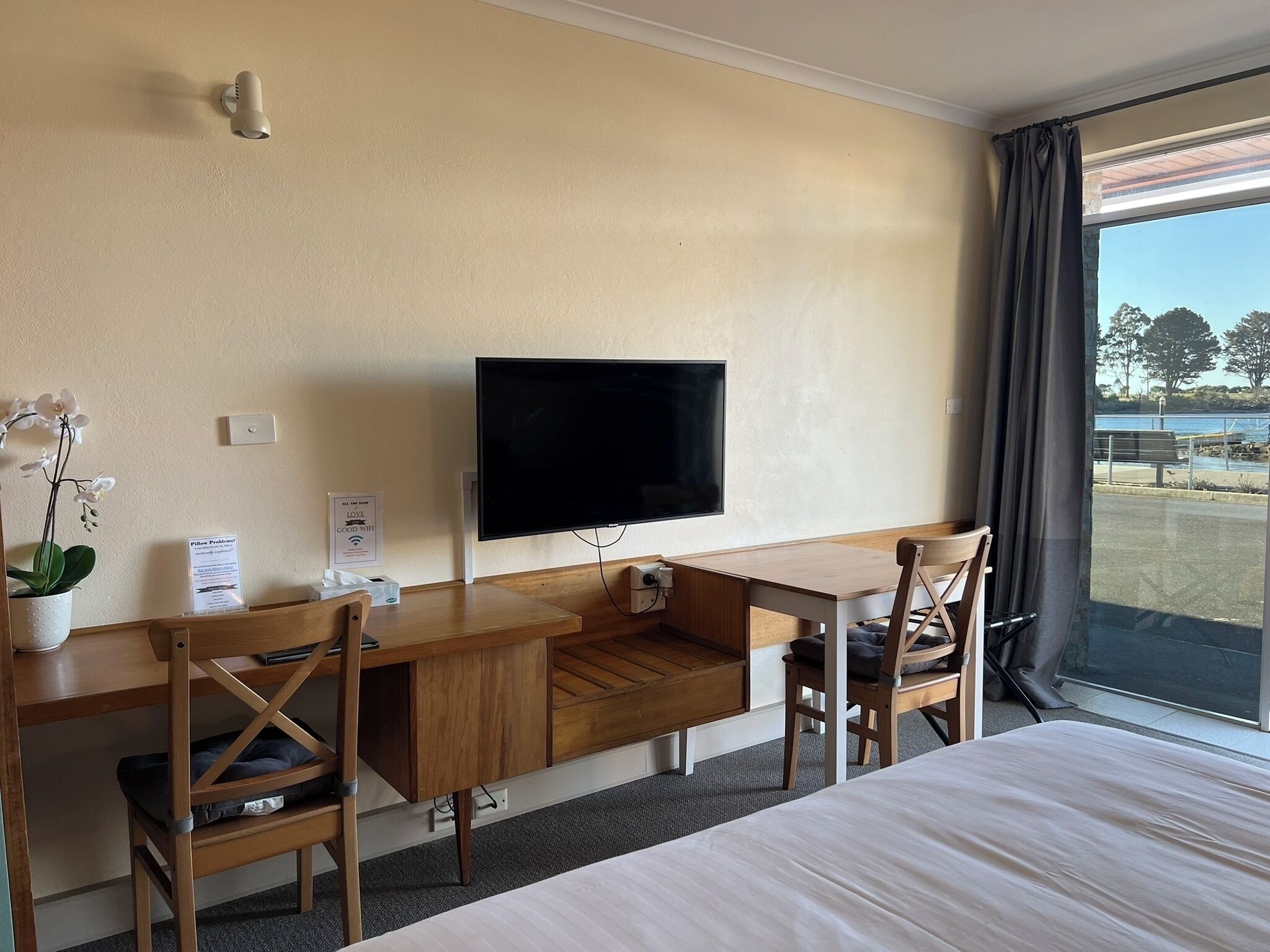 A hotel room with a bed, a desk with a chair, a television, and a window with a view of the outdoors.
